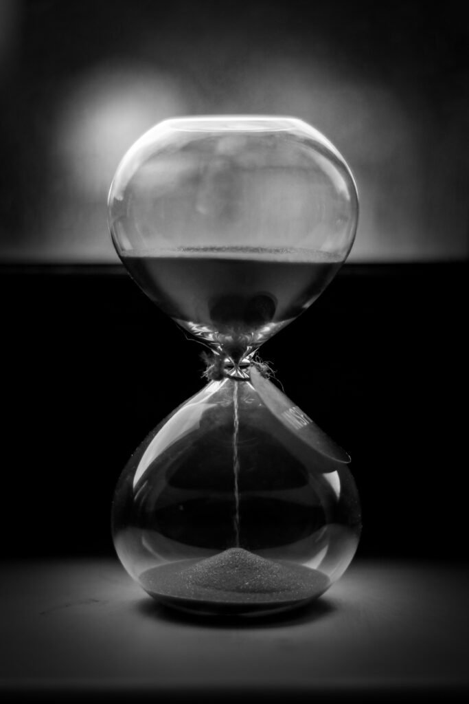 Elegant black and white image of an hourglass with sand falling, symbolizing time.