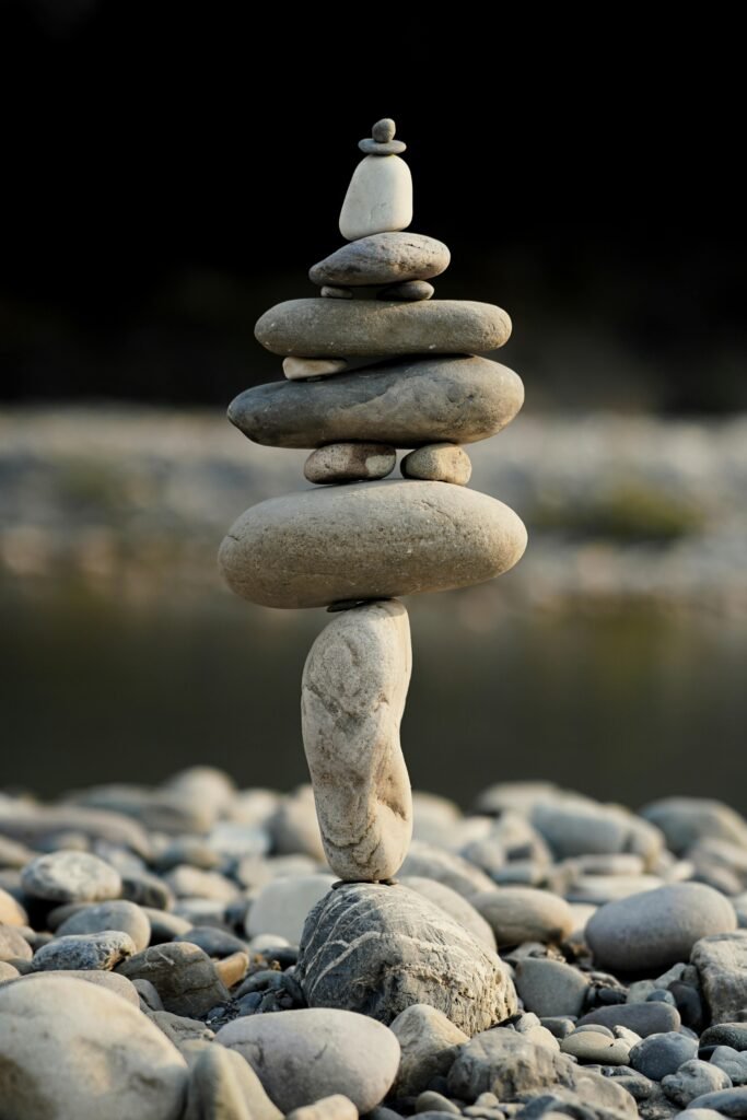 A vertical stack of smooth stones balancing by a tranquil riverside, symbolizing peace and harmony.