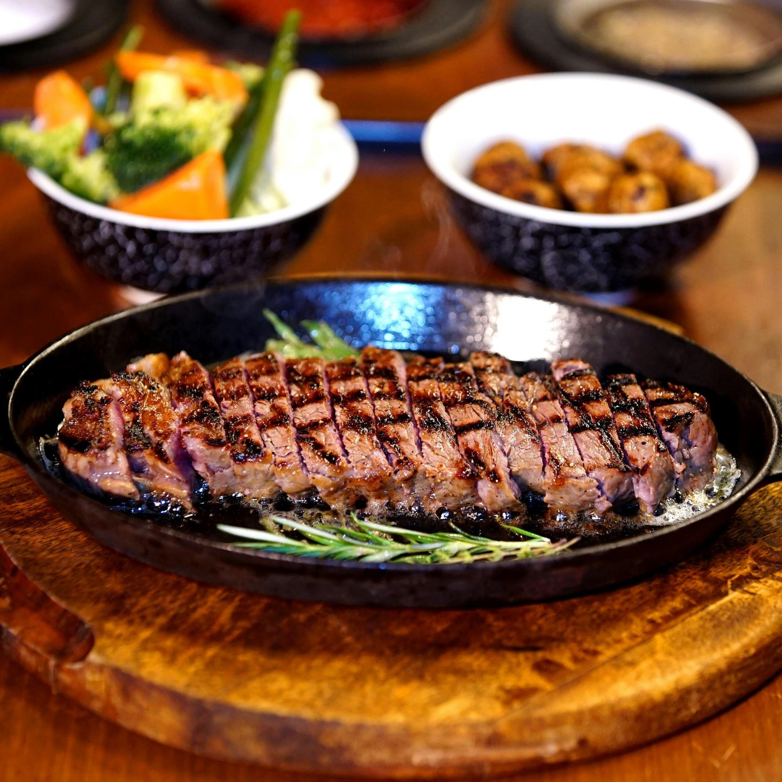 Deliciously grilled steak with vegetables served on a cast iron plate, perfect for a gourmet meal.