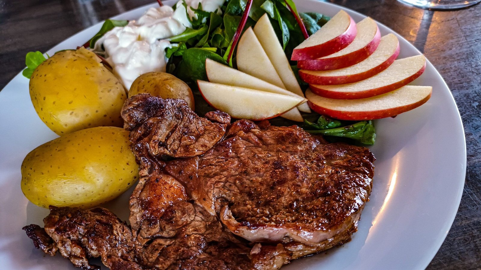 pexels photo 36879799 36879799 Delicious grilled steak with potatoes, fresh salad, and apple slices on a white plate.