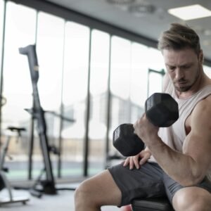 Focused man working out with a dumbbell in a well-equipped gym for strength training.