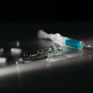 Close-up of syringes and capsules in selective focus with dramatic lighting.